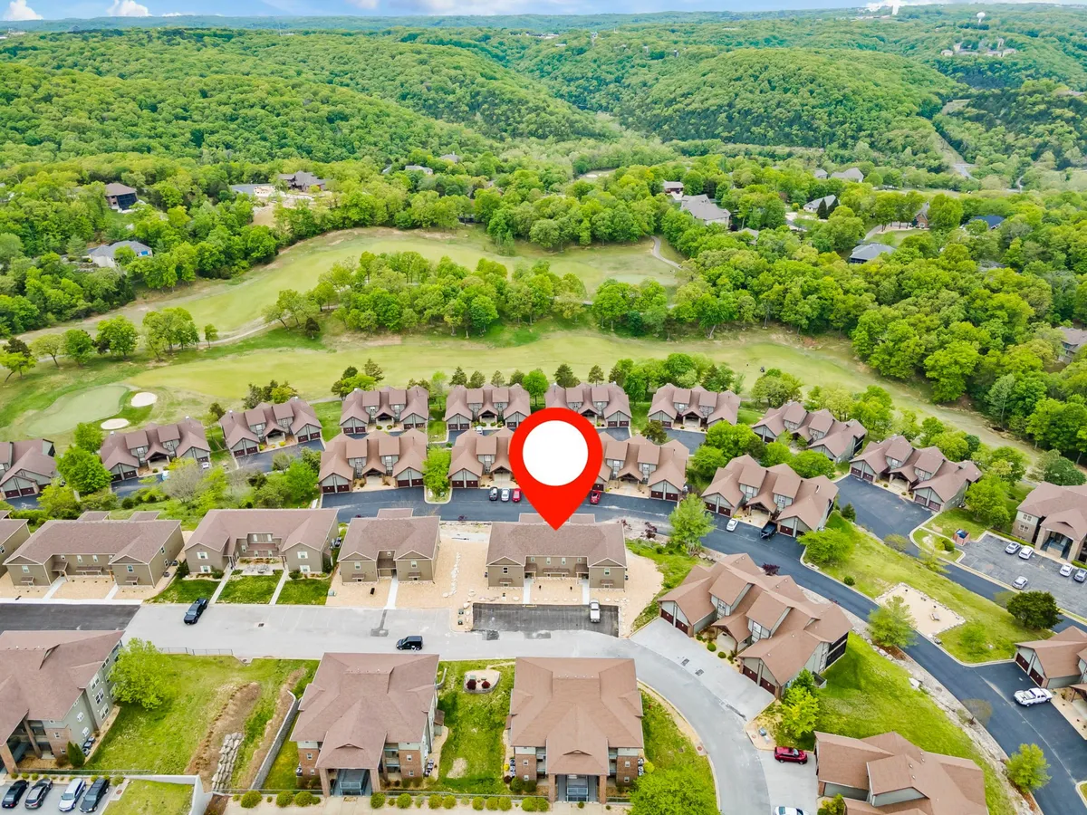 A sweeping exterior view of Stonebridge Resort’s residential buildings nestled among green landscapes and a golf course, with the soft hues of sunset painting the horizon. The scene illustrates the broader context and beauty visible from the balcony vantage point.