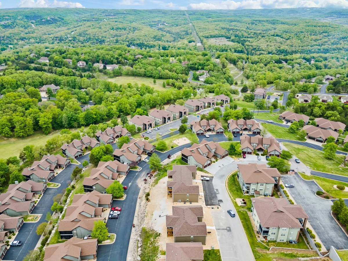 A wide view of the resort community, with residential buildings framed by winding roads, lush open spaces, and abundant trees. The setting looks peaceful and welcoming, ideal for exploring the grounds, biking, or family gatherings.