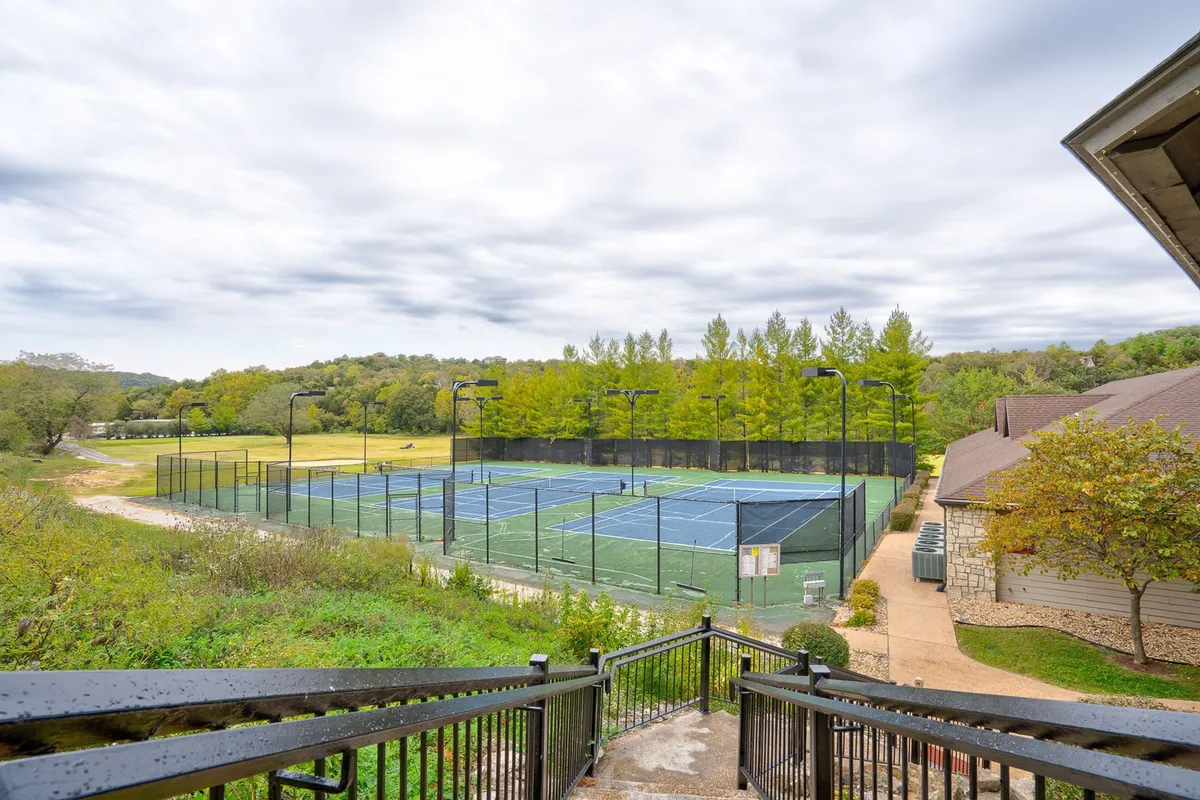 This exterior image features meticulously maintained tennis courts nestled among rich greenery, with a pathway leading through the area. It captures an active and healthy outdoor lifestyle, inviting visitors to enjoy sports and leisurely walks in nature's embrace.